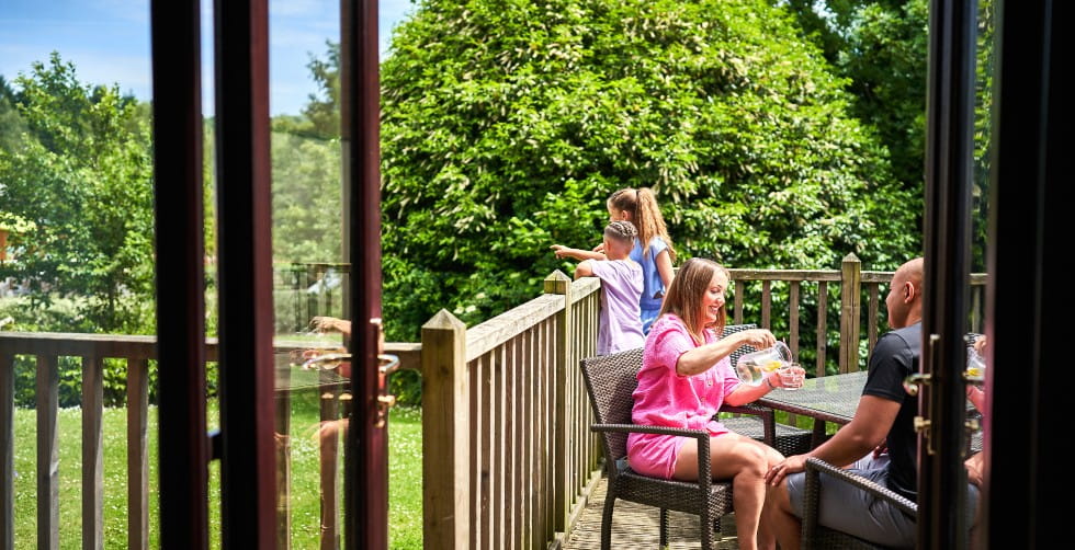 Family sitting on a Whitemead Forest Park log cabin balcony