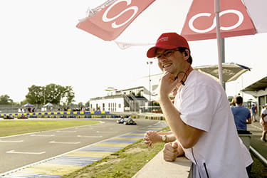 Man standing under parasol at a racetrack