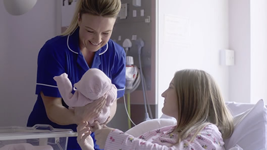 Midwife handing baby back to mother