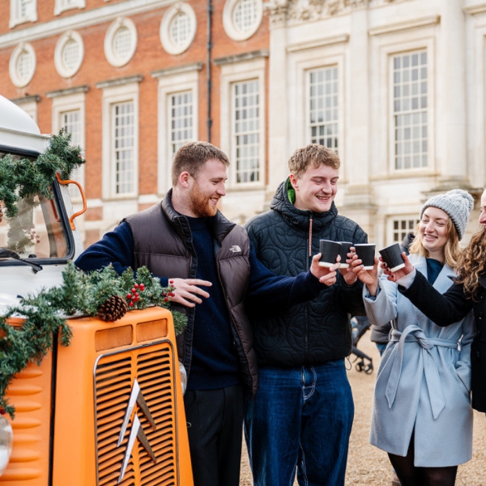 an image of 4 people outside of hampton court palace drinking hot drinks