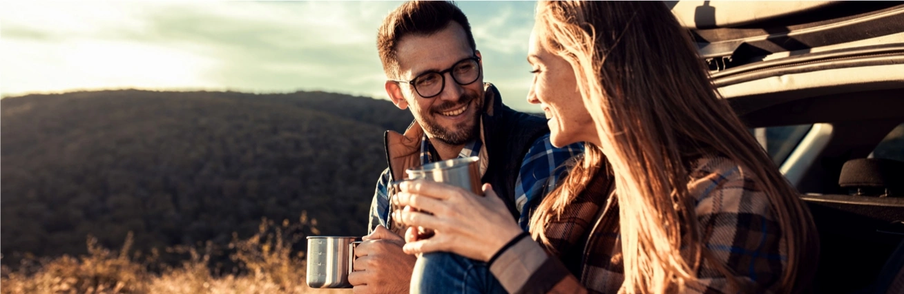 A couple enjoying a coffee while sitting on a car boot